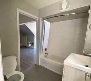 Hamilton apartment for rent - A white toilet is in a bathroom with a white tub and sink.