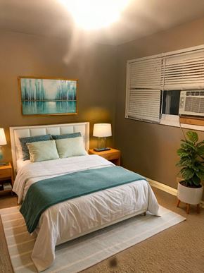 Cambridge house for rent - A bedroom with a bed, a lamp, a plant, and a painting on the wall.