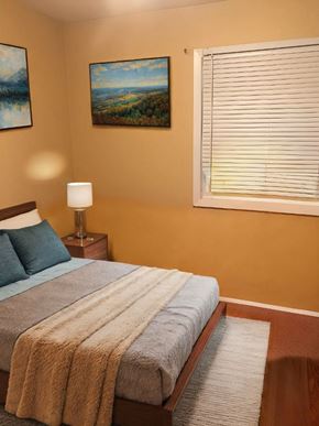 Cambridge house for rent - A bedroom with a bed, a lamp, and two paintings on the wall.