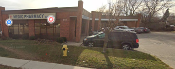 Cambridge apartment for rent - A black SUV is parked in front of a brick building with a sign that says "MEDIC PHARMACY.".