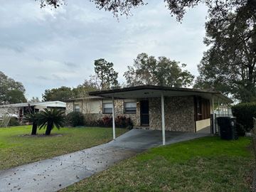 Apopka house for rent - A house with a driveway and a tree in front.