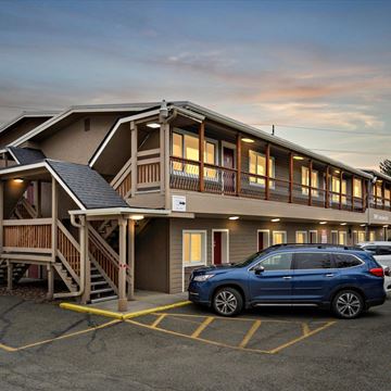 Anchorage apartment for rent - A blue SUV is parked in a parking lot in front of a building with a wooden deck.