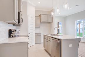 Youngsville house for rent - A modern kitchen with stainless steel appliances and white cabinetry.