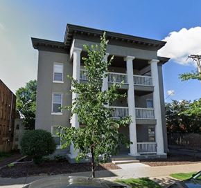 Minneapolis apartment for rent - A tree stands in front of a two-story building with white columns.