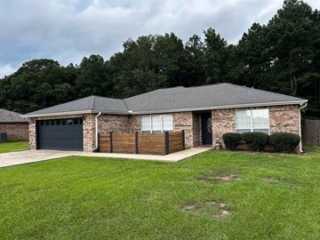 Deridder house for rent - A house with a grey roof and a black garage door.