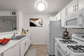 Reno apartment for rent - A kitchen with white cabinets and a white stove top oven.