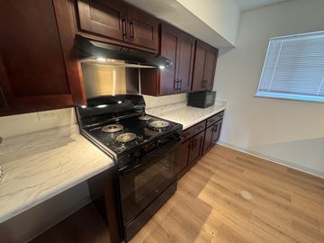 Grinnell apartment for rent - A kitchen with a black stove top oven and wooden cabinets.