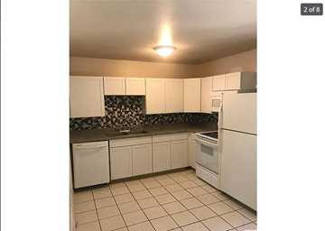 St. Louis house for rent - A kitchen with white appliances and a black and white backsplash.