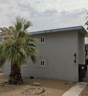 Las Vegas apartment for rent - A grey house with a blue roof and a palm tree in front.
