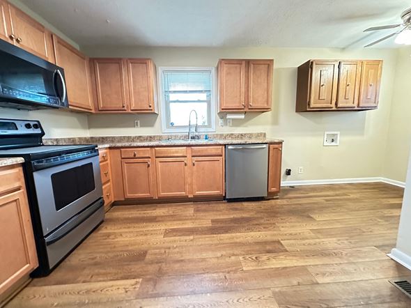Fayettevillle house for rent - A kitchen with wooden cabinets and a black stove top oven.