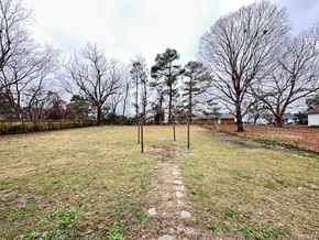 Fayettevillle house for rent - A grassy field with a path leading to a fence and trees.