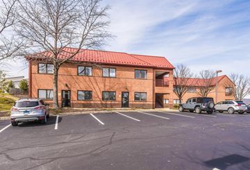 Frederick apartment for rent - A parking lot in front of a red building with cars parked.