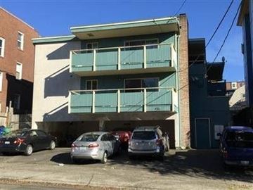 Seattle apartment for rent - A parking lot with cars and a building with balconies.