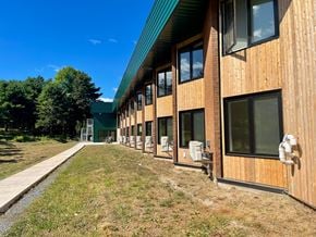Lunenburg apartment for rent - A long building with a green roof and wooden exterior.