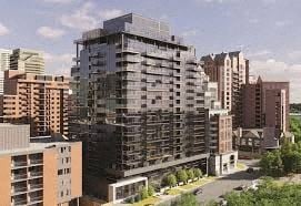 Calgary apartment for rent - A large building with many windows is in the middle of a city.