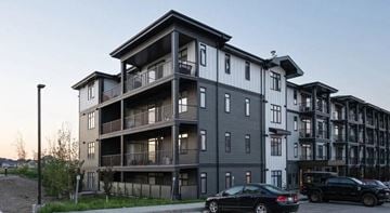 Calgary apartment for rent - A black car is parked in front of a modern apartment building.