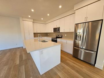 Airdrie house for rent - A modern kitchen with a stainless steel refrigerator and wooden flooring.