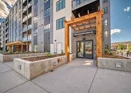 Calgary apartment for rent - A modern building with a wooden entrance gate and planters in front.