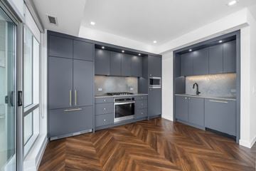 Calgary apartment for rent - A modern kitchen with dark grey cabinets and wooden flooring.