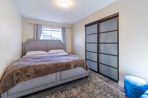Victoria apartment for rent - A bedroom with a bed, a window with curtains, and a blue chair.
