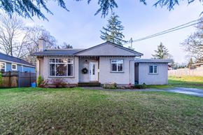 Victoria apartment for rent - A house with a grey roof and a white door is surrounded by a green lawn.