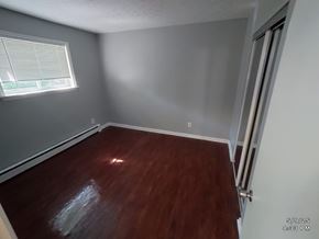 Norwood apartment for rent - A room with a wooden floor and a window with blinds.