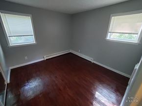 Norwood apartment for rent - A room with wooden floors and two windows.