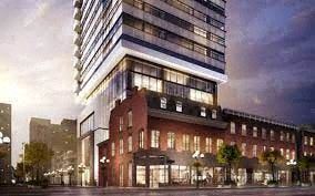 Toronto apartment for rent - A modern building with a glass facade is illuminated from within, set against a twilight sky.