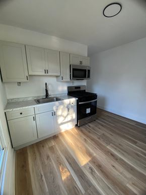Louisville apartment for rent - A kitchen with wooden floors and white cabinets.