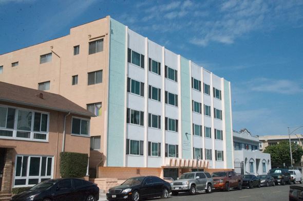 Long Beach apartment for rent - A large building with a white and blue facade is surrounded by parked cars.