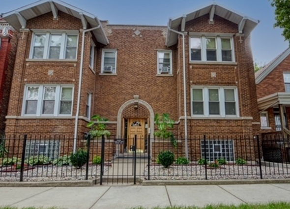 Chicago apartment for rent - A red brick house with a black iron fence in front.