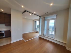 Toronto apartment for rent - A spacious room with wooden floors and a large window with a view of the outside.