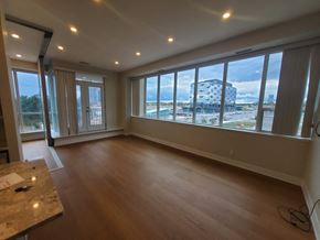 Toronto apartment for rent - A room with wooden floors and a marble table with a view of a pool and buildings outside the window.