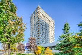 Toronto apartment for rent - A tall building stands in front of a clear blue sky with trees in the foreground.