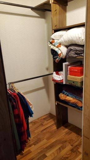 Ligonier house for rent - A closet with clothes hanging and shelves with boxes and a pillow.