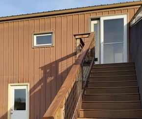 Ligonier house for rent - A brown house with a staircase leading to a glass door.