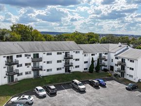 Norristown apartment for rent - A white building with a black sign on the front and a tree in front of it.