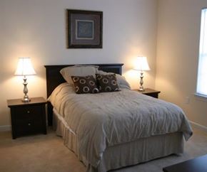 Greenville condo for rent - A bedroom with a large bed and two lamps on either side of the bed.