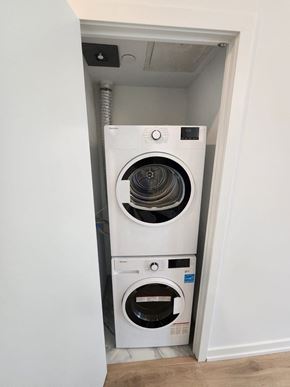 Toronto apartment for rent - A white washing machine and dryer in a small, white-walled laundry room.