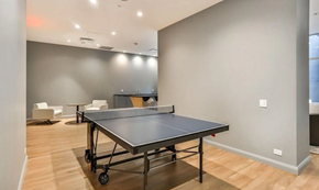 Toronto apartment for rent - A ping pong table is in the middle of a room with a wooden floor.