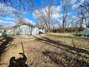Louisville house for rent - A person is taking a photo of a house with bare trees and a blue sky in the background.