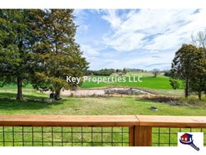 Madisonville house for rent - A fence with a view of a field and trees with Key Properties LLC written on it.
