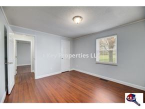 Madisonville house for rent - A room with wooden floors and a window with blinds.