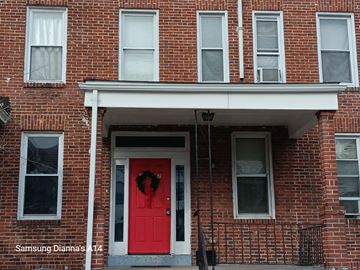 Baltimore apartment for rent - A red door with a wreath on it is the main focus of this image.