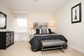 Ottawa apartment for rent - A bedroom with a black bed and a black chair.