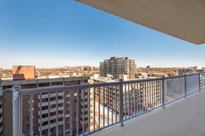 Cote St Luc apartment for rent - A balcony with a metal railing overlooks a cityscape.