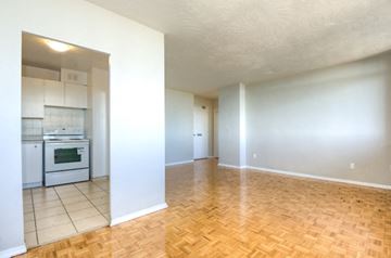 Toronto apartment for rent - A kitchen with white cabinets and a stove top oven is visible through a doorway.