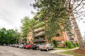 Mississauga apartment for rent - A parking lot with cars and a building in the background.