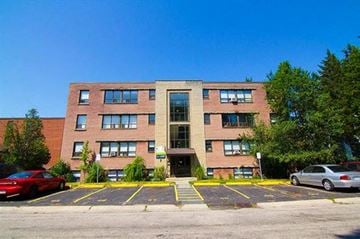 Hamilton apartment for rent - A multi-story building with a parking lot in front.