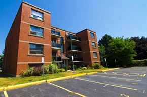 Hamilton apartment for rent - A parking lot in front of a red brick building.